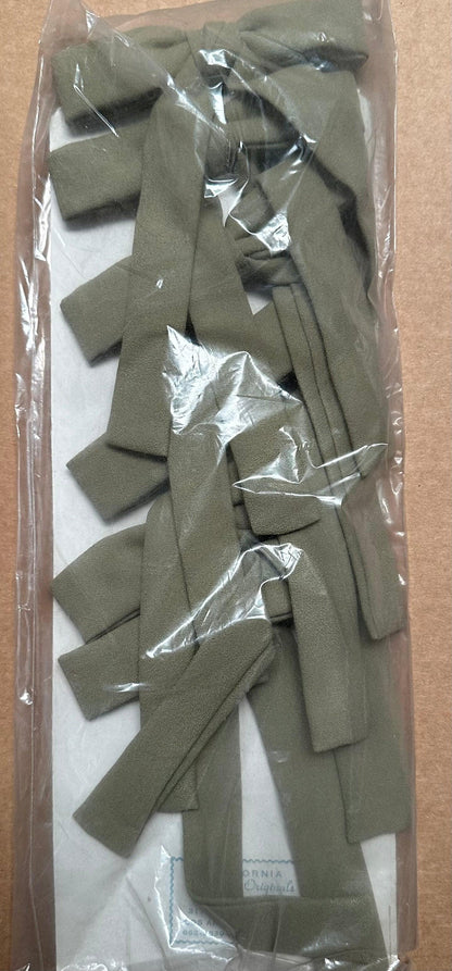 A package of Colonel Ties by Square Up Fashions, featuring folded olive-green fabric strips that evoke a rustic, old-fashioned western look, neatly tucked inside a clear plastic bag.