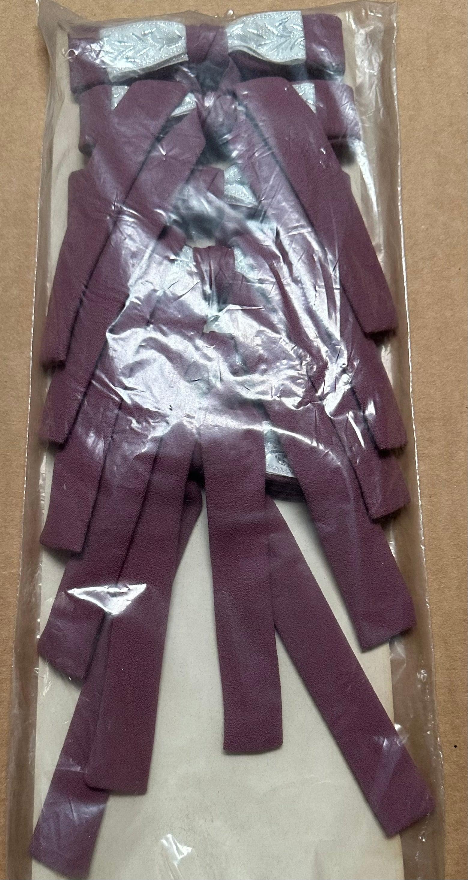 A package of Colonel Ties, featuring multiple maroon-colored fabric strips that resemble southern bow ties, is displayed flat in a clear plastic bag. This product is offered by Square Up Fashions.