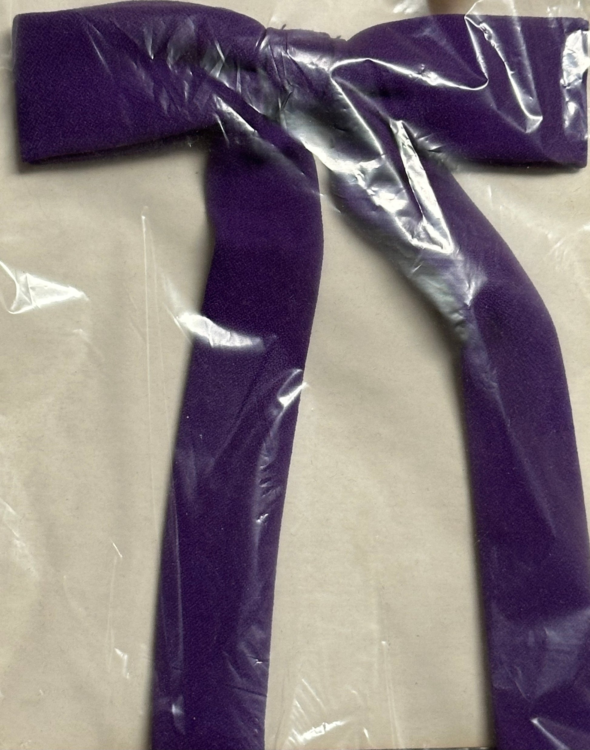 A purple Colonel Tie by Square Up Fashions, designed with an old-fashioned western style, is wrapped in clear plastic packaging on a plain background.