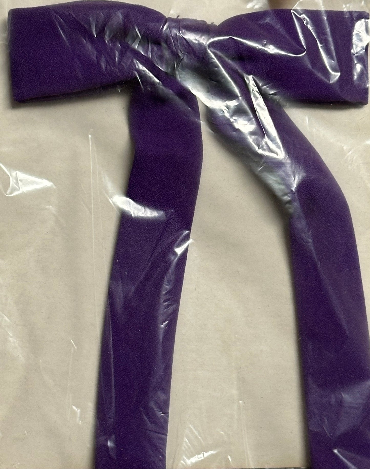 The Colonel Ties by Square Up Fashions, a purple fabric bow reminiscent of southern bow ties, is neatly wrapped in clear plastic packaging.