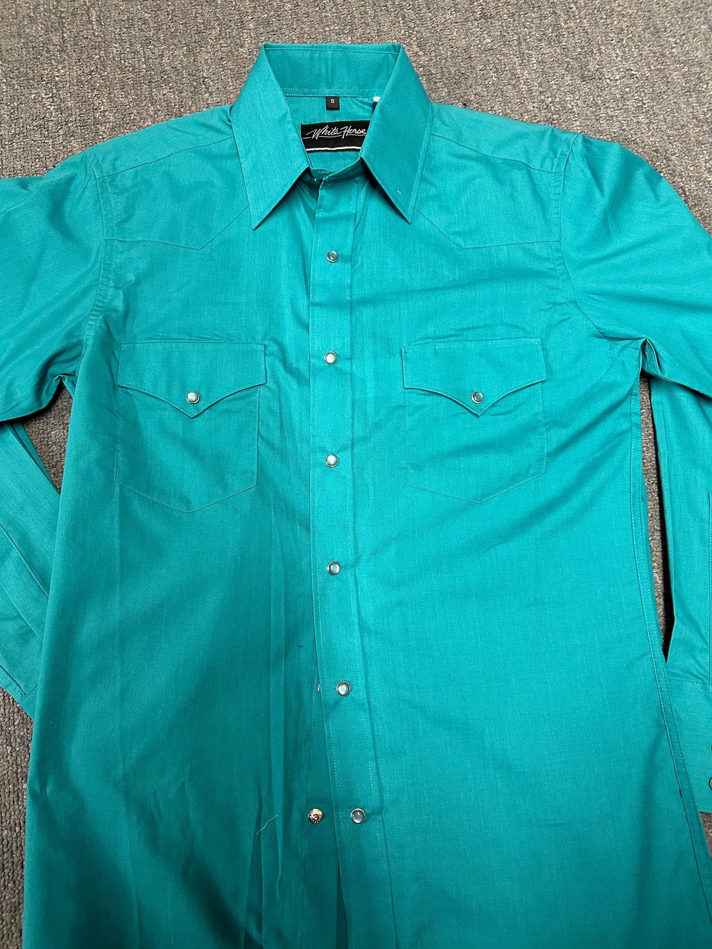 A men's WHITEHORSE brand western shirt in turquoise on the floor.